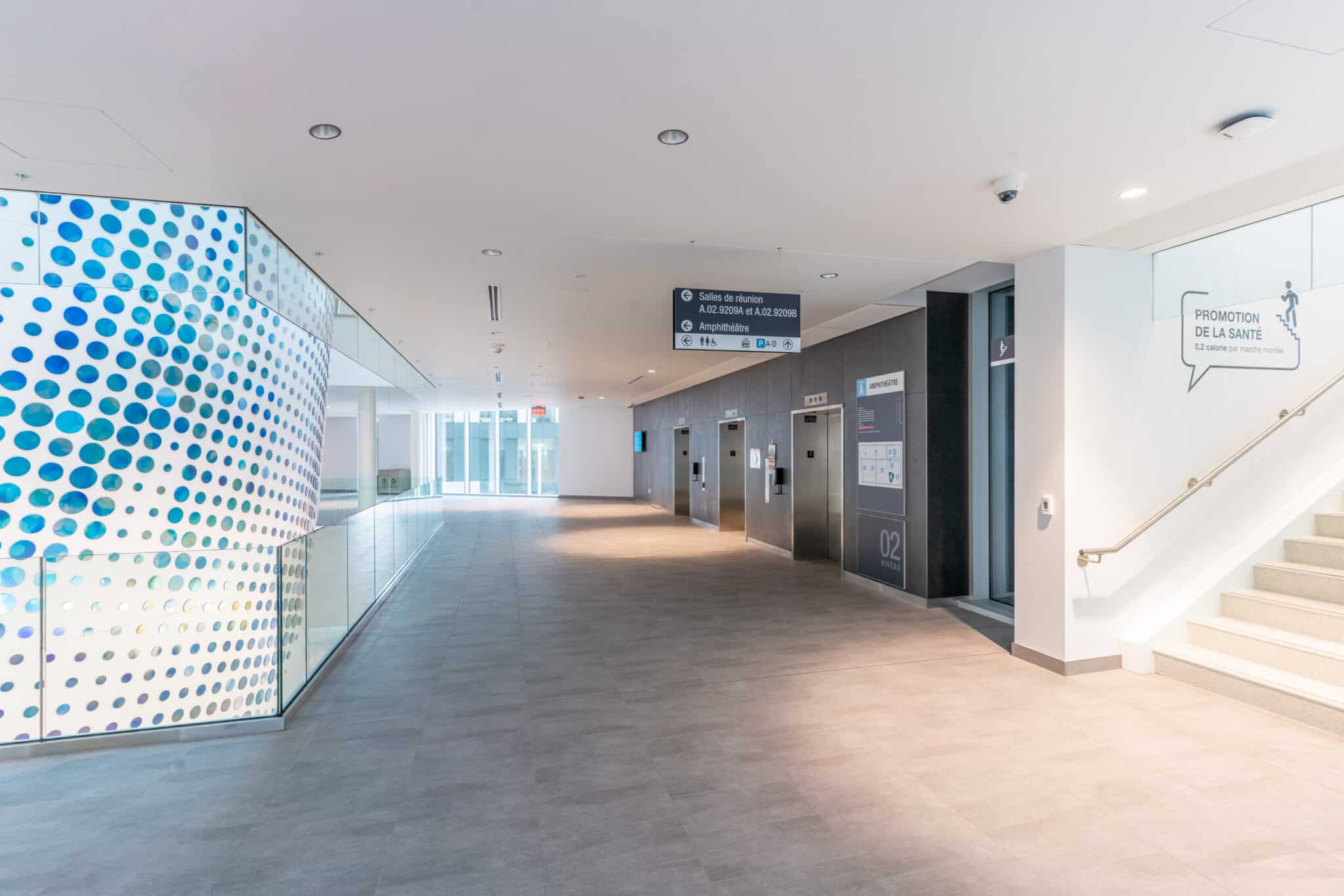 Arium Design - Intégration signalétique et harmonie architecturale du bloc d'ascenseurs principal du Centre hospitalier de l'Université de Montréal.