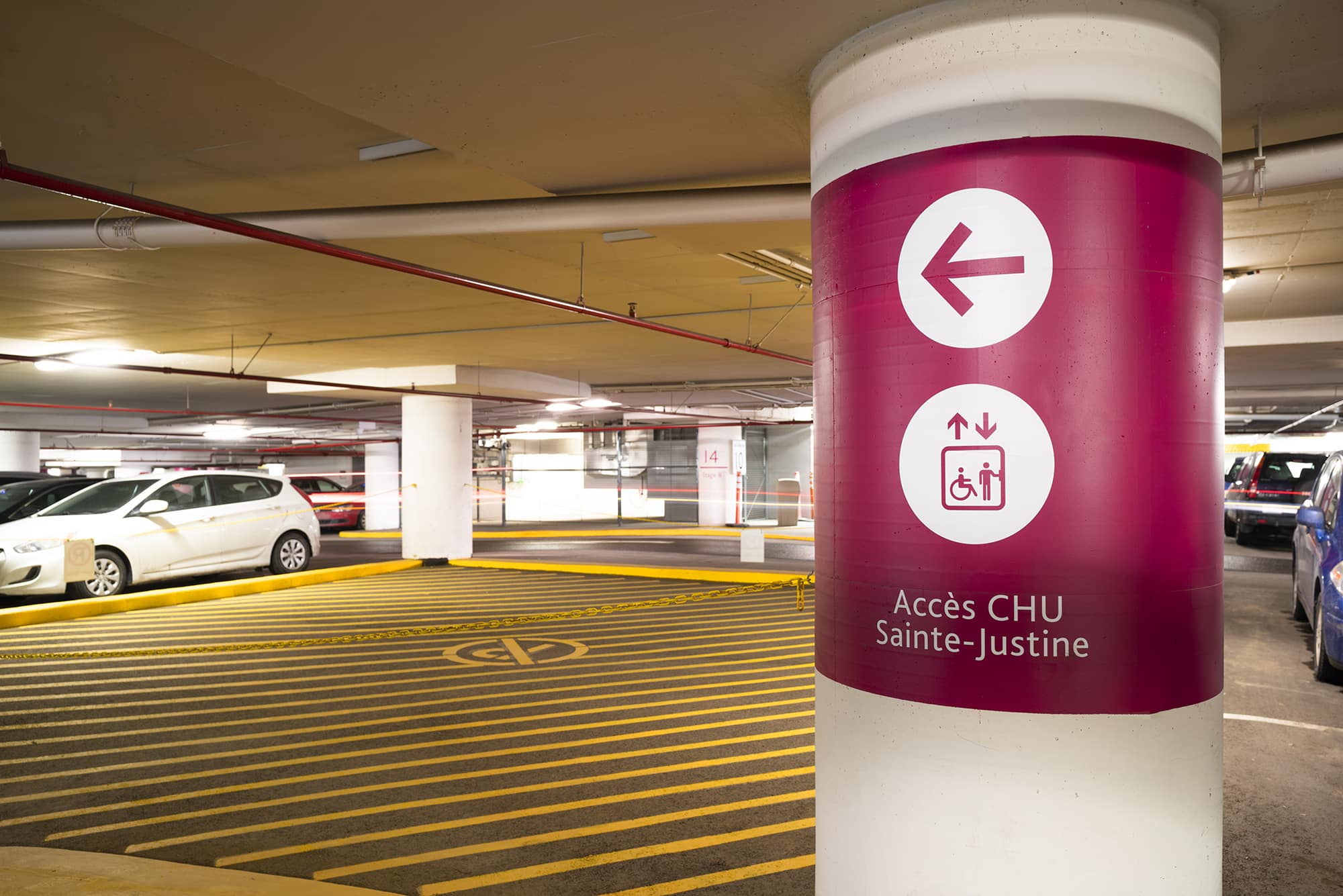 Arium Design - Directionnel sur colonne dans le stationnement souterrain menant aux ascenseurs de l'Hôpital Sainte-Justine.